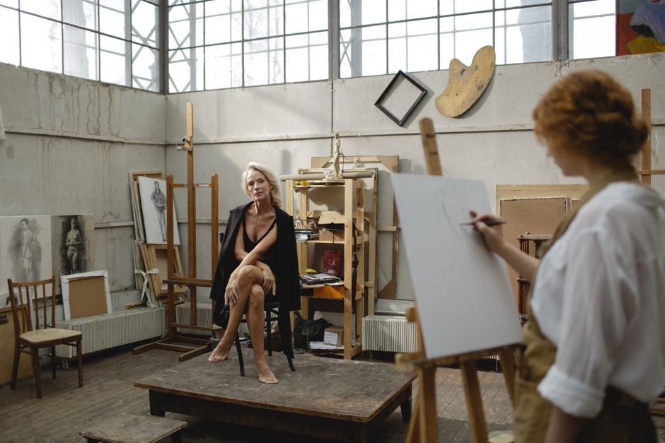 An artist sitting in front of a futuristic computer screen, typing a complex text prompt that materializes into a vibrant digital painting of a cosmic city.